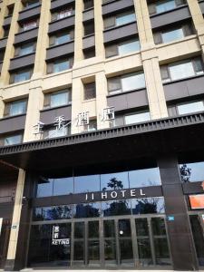 哈尔滨Ji Hotel Harbin West Railway Station的一座酒店大楼,前面有标志