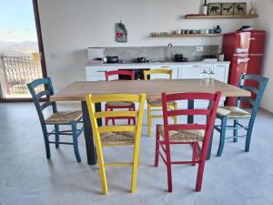 奥菲达Agriturismo San Nicolino的厨房配有带五颜六色椅子的木桌