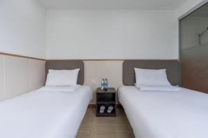上海Hi Inn Shanghai Global Harbor的配有2张床铺、白色床单和桌子的客房