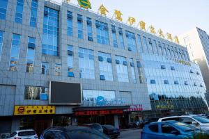 鄂尔多斯Hanting Hotel Ordos Yijinholoqi Wenming Road的一座大型建筑,前面有汽车停放