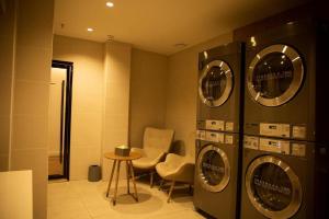 鄂尔多斯Hanting Hotel Ordos Yijinholoqi Wenming Road的洗衣房配有3台洗衣机和桌子
