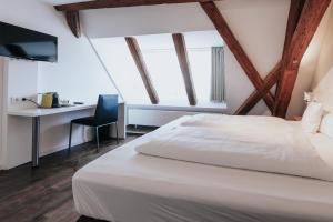 乌尔姆Design Hotel & Restaurant Löwen的卧室配有白色的床和书桌