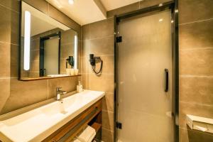 青岛Hanting Hotel Qingdao Xianggang Zhong Road Aofan Center的带淋浴、盥洗盆和镜子的浴室