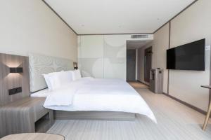 GuodianHanting Hotel Zhengzhou South Longhu Shawoli Metro Station的卧室配有一张白色大床和一台平面电视。