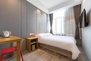 上海Hi Inn Shanghai Xujiahui Yongjia Road的一间卧室配有一张床、一张书桌和一个窗户。