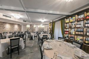 切拉诺Hotel Mastrodattia的一间设有白色桌椅的餐厅,并提供葡萄酒瓶