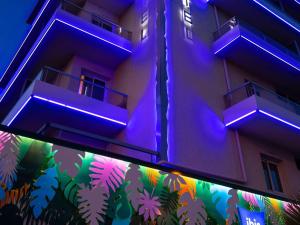 芒通芒通海岸宜必思快捷酒店的建筑的侧面有紫色的灯