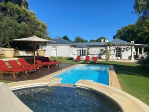 斯泰伦博斯Banhoek Corner Guesthouse的一个带红色椅子的游泳池