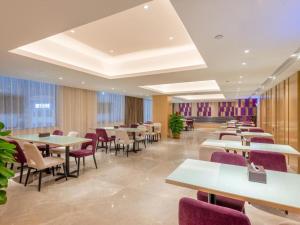 ShilongLavande Hotel Dongguan Shijie Jiarong Shopping Plaza Liuhua Metro Station的一间带桌椅和紫色椅子的餐厅
