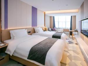 惠州Lavande Hotel Huizhou World Trade Center的酒店客房设有两张床和电视。