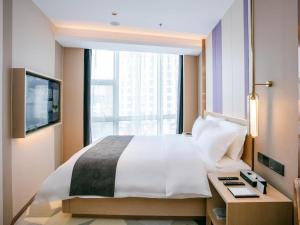 惠州Lavande Hotel Huizhou World Trade Center的一间卧室设有一张大床和一个窗户。