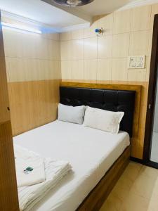 孟买Hotel Sagar Residency的一张配有白色床单和枕头的大床