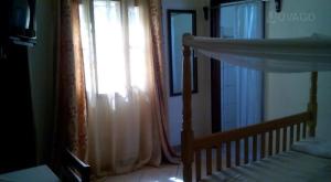金贾Trinity Guest House的一间卧室配有床和带窗帘的窗户