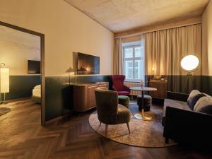 巴德加斯坦Straubinger Grand Hotel Bad Gastein的酒店客房,配有沙发、椅子和一张床