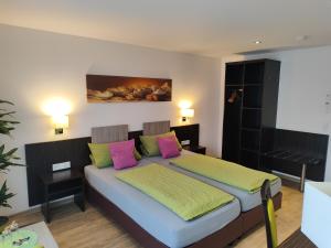 腓特烈港Hotel Gästehaus Stock Zimmer Brotkörble的一间卧室配有带粉色和绿色枕头的床