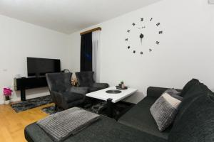 Sanski mostGOLD Apartman的客厅配有沙发和墙上的时钟
