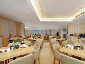兴仁Vienna Hotel Guizhou Xingren的配有木桌和白色桌椅的餐厅