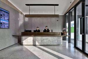 苏州Meijin All Suites Hotel Suzhou的两名男子坐在大堂的前台