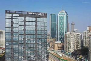 苏州Meijin All Suites Hotel Suzhou的一座高大的建筑,上面有城市的标志