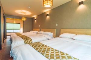 大阪Bijou Suites Kakomi的带3张白色床单的床的房间