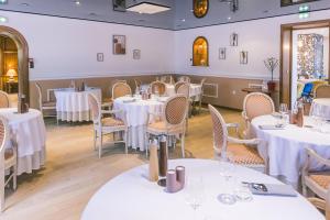 蒙蒂尼雷斯LOGIS Hôtel & Restaurant Le Soleil D'or的一间设有白色桌椅的用餐室