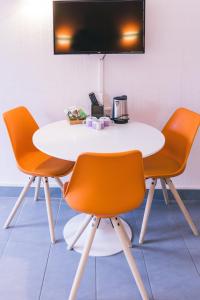 蒙蒂尼雷斯LOGIS Hôtel & Restaurant Le Soleil D'or的一张带橙色椅子的白色桌子和墙上的电视