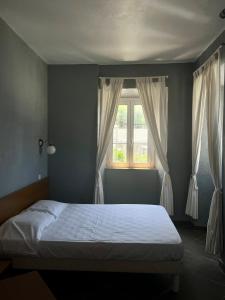 森图里L’Auberge du pêcheur的一间卧室配有床和带窗帘的窗户