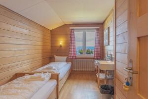 贝阿滕贝格Berghaus Niederhorn的小房间设有两张床和盥洗盆