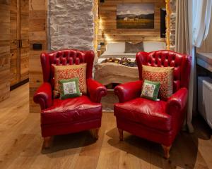 阿夏戈Asiago Sporting Hotel & Spa的卧室里设有两张红色椅子和一张床