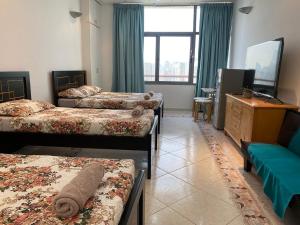 阿布扎比J & F Homestay - Abu Dhabi的酒店客房设有三张床和电视。