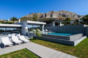 苏尼翁Luxury Beachfront Villa Selenia Gold in Sounio的一座带游泳池和白色椅子的房子
