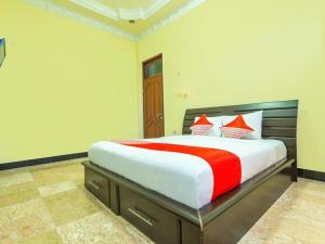 马塔兰Senaz Guesthouse的一间卧室配有一张带红色和白色枕头的大床