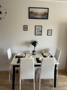 利耶帕亚Baltic Apartament的一间带桌子和白色椅子的用餐室