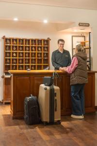 圣马丁德洛斯夏特勒酒店的一名男子和一名女子带着行李站在柜台上