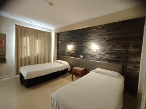 埃尔阿雷纳尔银海旅馆的酒店客房带两张床和砖墙