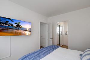 圣地亚哥Surf Shack 2的一间白色卧室,墙上配有电视