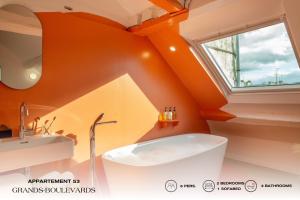 巴黎Beauquartier - Grands Boulevards的橙色浴室设有浴缸和水槽