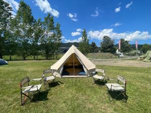 施皮尔贝格GrandPrixCamp, closest to the Red Bull Ring, up to 4 guests in a tent的田野里一组椅子和帐篷