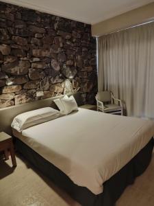 埃尔阿雷纳尔银海旅馆的一间卧室设有一张大床和石墙