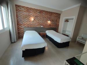 埃尔阿雷纳尔银海旅馆的一间设有两张床和砖墙的房间