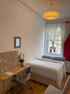 伦敦15 min to The Heart of London - Charming 2 bed Apartment的一间卧室配有一张床、一张书桌和一个窗户。