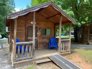 索尔兹伯里Homely Poolside Cabin的小木屋,门廊上摆放着2把蓝色椅子