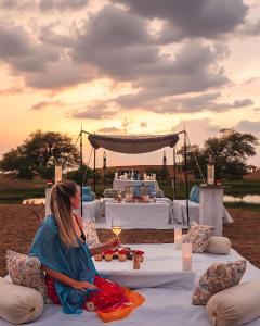斋沙默尔Jaisalmer Sam Sand Dunes Luxury Camps的坐在桌子前沙发上的女人