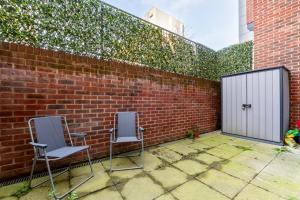 伦敦GuestReady - Modern lodge with garden的两把椅子坐在砖墙旁的庭院