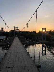 爱妮岛Bucana Beach Camp的日落时分水面上的桥梁