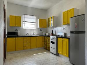 圣菲利普Lailamar Villa, Ocean view & Pool - Entire Villa的厨房配有黄色橱柜和冰箱