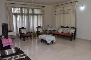 迈索尔MAHAMAYA HOME STAY的客厅配有椅子、桌子和电视