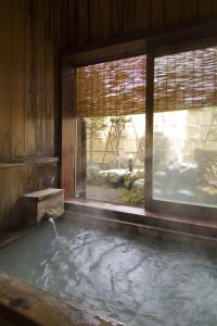 草津益成屋日式旅馆的带窗户的客房内配有水浴缸