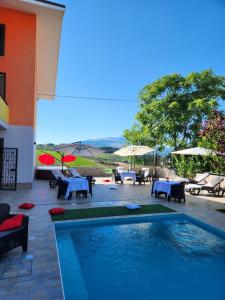 Villa BadessaAndale SuiteSpa的庭院内一个带桌子和遮阳伞的游泳池