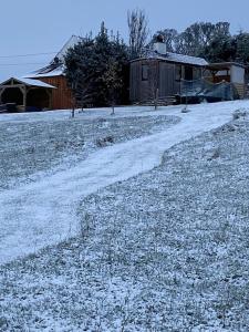 邓弗里斯Stunning Shepherds Hut rural bliss Dumfries的一片雪覆盖的田野,有房子和土路